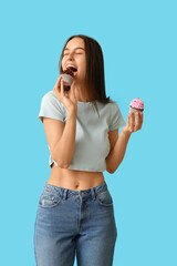 Obraz premium Young woman with sweet cupcakes on blue background. Valentines Day celebration