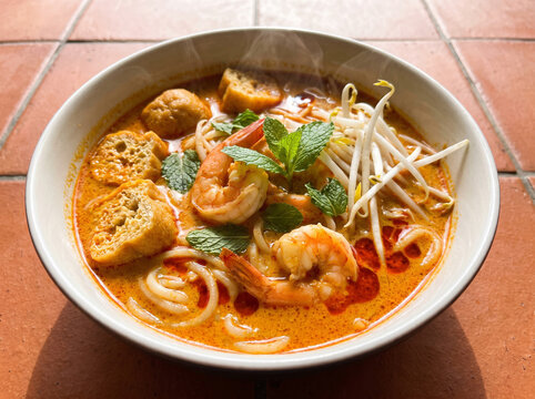 Malaysian curry laksa noodle soup with coconut broth prawns tofu puffs bean sprouts and chili oil