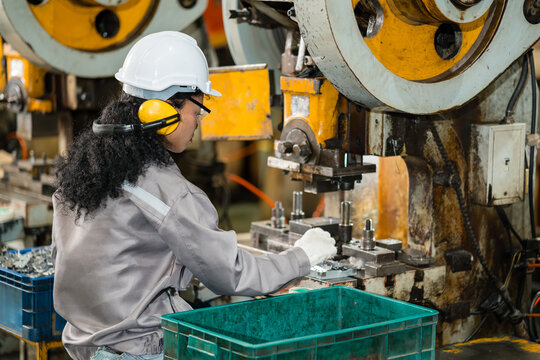 Female machine operator placing a metal stamped part into a power press die