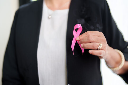 Businesswoman holding pink ribbon for breast cancer awareness and health campaign