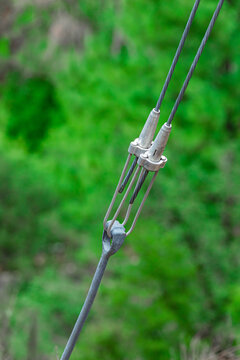 Close up view of steel guy wire cable tensioner attached to a pole anchor with blurred green background