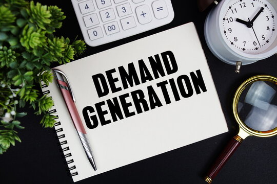 Demand Generation text written on notepad with alarm clock, magnifying glass and calculator on black background