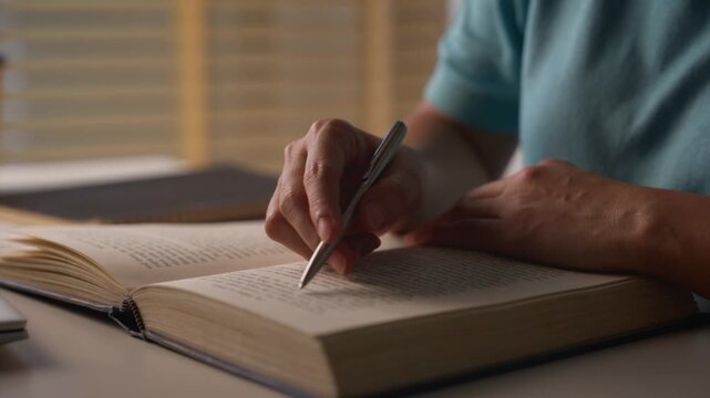 Close up of Asian woman reading a book on desk at home. Lifestyle and education concept.