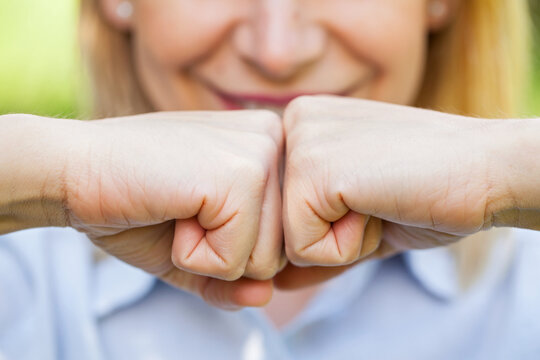 Smiling Woman Holding Clenched Fists Together With Confidence