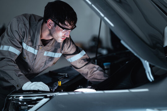 An experienced mechanic performs electrical diagnostics using professional digital testing equipment inside a modern automotive repair workshop. Ideal for concepts involving automotive electronics,
