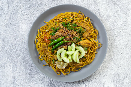 Javanese fried noodles Bakmi Goreng Jawa, stir-fried noodles served with egg, chicken, and cucumber pickles