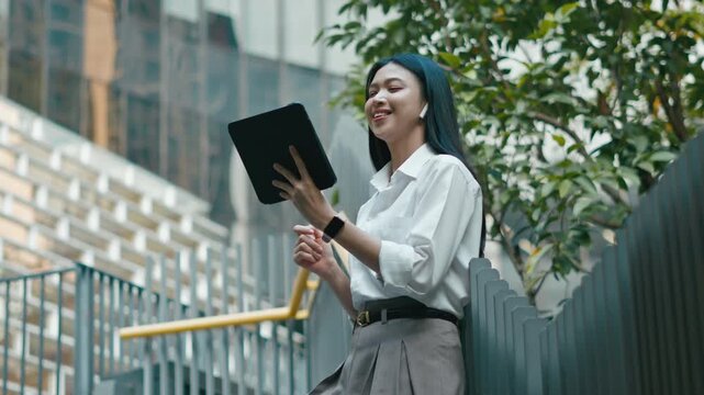 successful asian business woman using phone or digital tablet in front of modern business building.Portrait of businesswoman outdoors.
