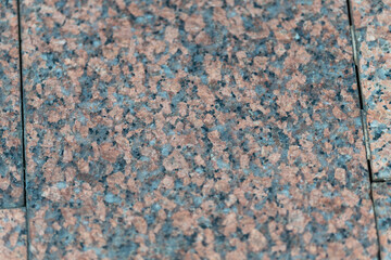 Fototapeta premium Granite tiles with a blend of colors create a mesmerizing texture for outdoor spaces in a sunny afternoon setting
