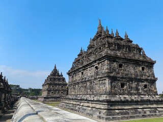 Ancient stone temple stands tall against clear blue sky © Ooh Seha