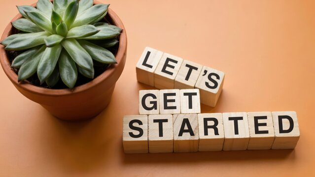 LET'S GET STARTED message on wooden blocks with a succulent plant on an orange background