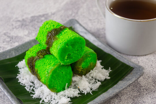 Traditional Indonesian steamed rice flour cake or kue putu bambu filled with melted palm sugar and served over grated coconut on a banana leaf
