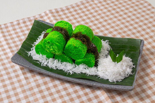 Traditional Indonesian steamed rice flour cake or kue putu bambu filled with melted palm sugar and served over grated coconut on a banana leaf