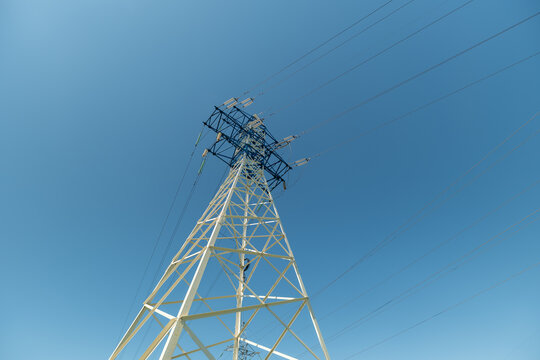 High voltage power line tower against a clear blue sky during the day