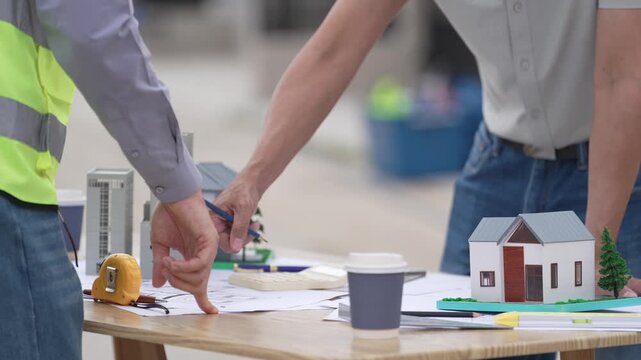 Architect and Civil Engineer Discussing Building Plans with Architectural Models and Blueprint on Worktable