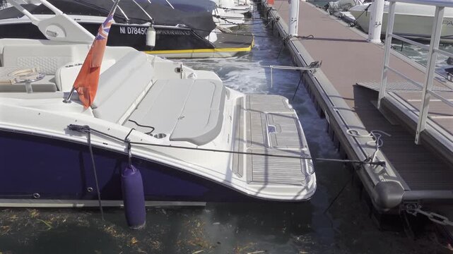 Motorboat moving forward at dock with choppy water leaving wake and showing british flag.
