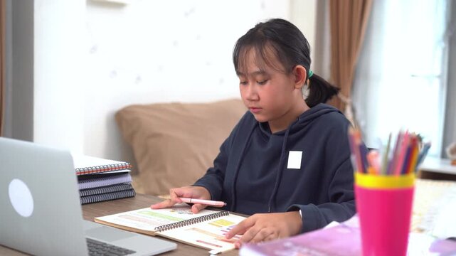 Young girl study diligently and carefully took notes on important points from the online lessons at home