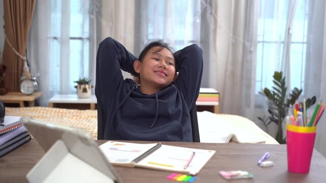Young girl is happy and relaxed after finishing her homework at study desk at home