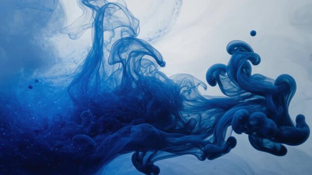 Abstract blue ink swirling in water creating beautiful fluid shapes and patterns with soft lighting