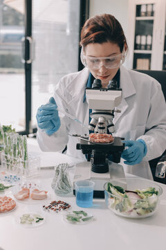 Scientists in lab coats work with plants in a modern lab, focusing on research and experimentation under bright, sterile conditions.