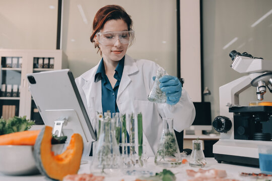 Scientists in lab coats work with plants in a modern lab, focusing on research and experimentation under bright, sterile conditions.
