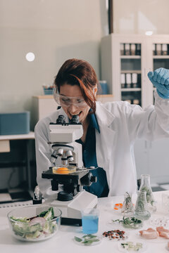 Scientists in lab coats work with plants in a modern lab, focusing on research and experimentation under bright, sterile conditions.