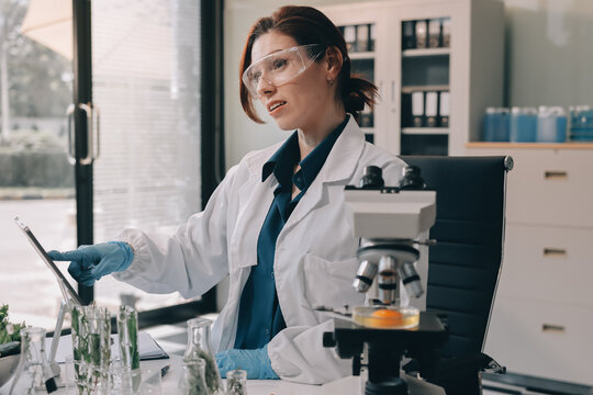 Scientists in lab coats work with plants in a modern lab, focusing on research and experimentation under bright, sterile conditions.