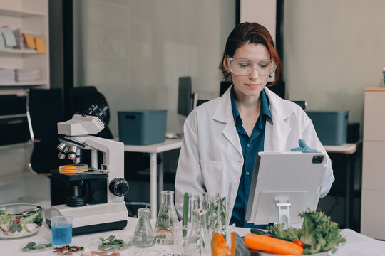 Scientists in lab coats work with plants in a modern lab, focusing on research and experimentation under bright, sterile conditions.