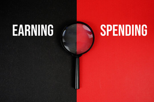 EARNING vs SPENDING text with magnifying glass on black and red background