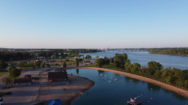 Drone shot of Ashwaubenon Park in Green Bay Wisconsin Area.  Kids playing on water slide at lagoon off the fox river at sunset.  
