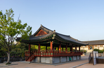 Naklejka premium Traditional Korean pavilion architecture with red pillars and tiled roof against clear blue sky