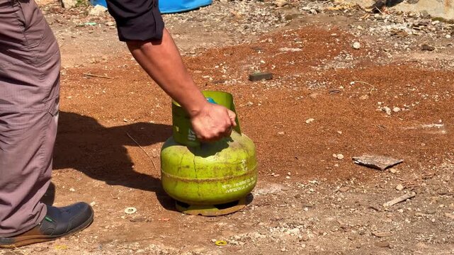 Person demonstrating gas cylinder leak fire hazard for safety training. Fire safety, emergency drill, and LPG hazard concept outdoor footage.