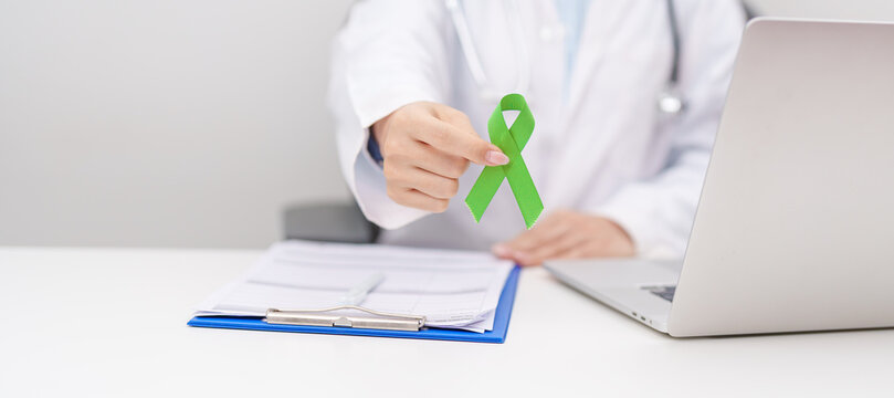 Doctor give lime Green Ribbon for concept of May Celiac Awareness month, Lyme disease, September Lymphoma, Mental Health Awareness month and October Liver cancer. Health and world cancer day