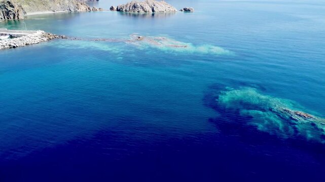 Drone footage showcasing the crystal-clear turquoise waters, rocky reefs and tranquil coastline of Skala Eressos Beach on Lesvos Island, Greece, on a sunny summer day.