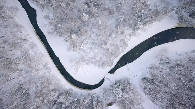 Drone footage of a winding river flowing through a snow-covered landscape in Northern Michigan.