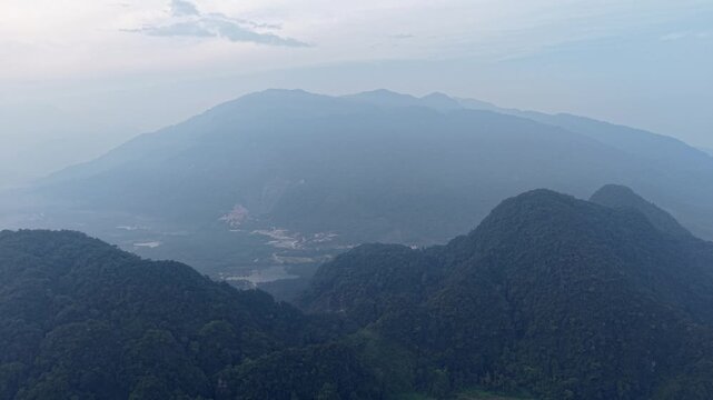 Soft morning light on mountain peaks. Mist softens distant ridges. Valleys cradle sleepy villages at Kampar, Perak