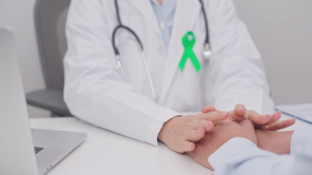 doctor holding patient hand to comfort and support with empathy. lime Green Ribbon for concept of May Celiac Awareness month, Lyme disease, September Lymphoma, Mental Health and Liver cancer