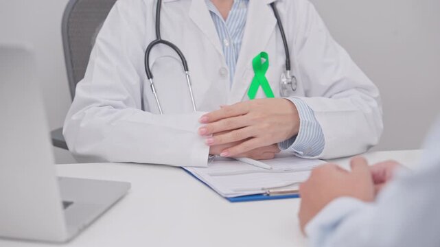 Doctor and patient having a medical consultation for lime Green Ribbon for concept of May Celiac Awareness month, Lyme disease, September Lymphoma, Mental Health Awareness month and Liver cancer