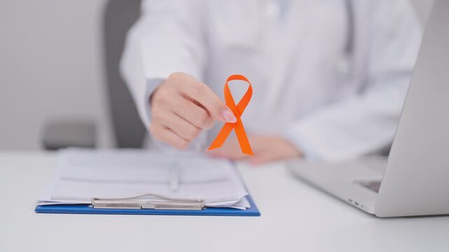 Doctor wearing lab coat giving orange ribbon for September Leukemia, March Kidney, August Appendix cancer, Multiple Sclerosis, Self Injury, November Complex Regional Pain Syndrome, CRPS and COPD