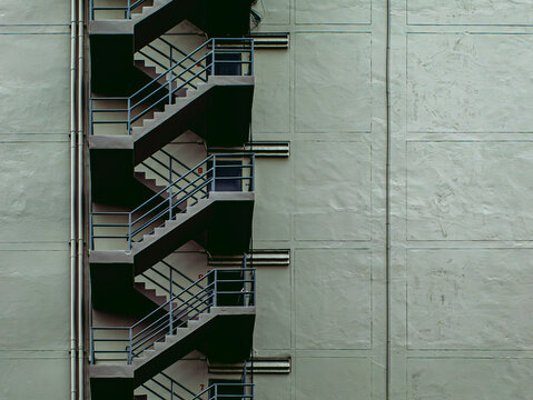 Exterior Zigzag Fire Escape Staircase on Green Concrete Apartment Building