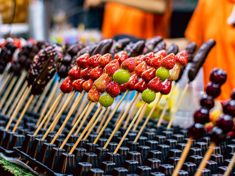 Rows of Glazed Candied Fruit Skewers Strawberry Grape Chocolate Banana