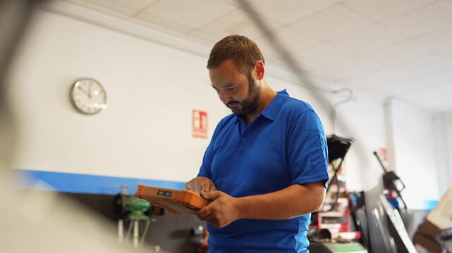 Auto mechanic using diagnostic tool in workshop