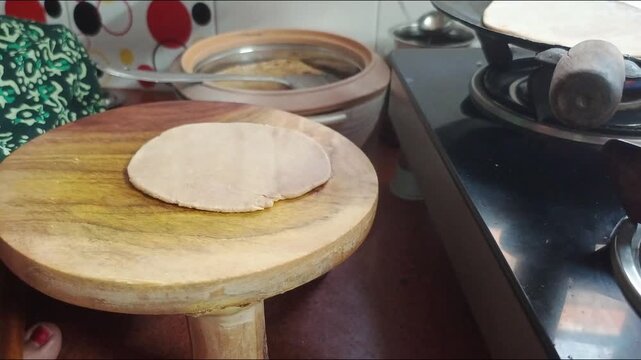 Indian Woman Making Traditional Paratha Rolling Dough and Frying on Tawa in Kitchen