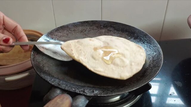 Indian Woman Making Traditional Paratha Rolling Dough and Frying on Tawa in Kitchen