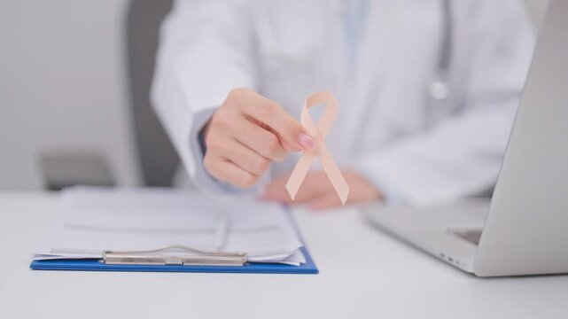 Doctor giving peach ribbon to patient for concept of September Uterine Cancer Awareness month, Endometrial Cancer, Gynecologic, Uterus and Ovaries, Endometriosis, June Vaginal cancer and World cancer