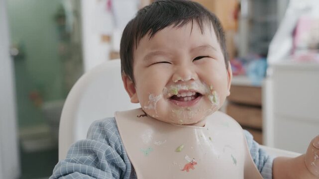 Asian baby boy self feeding sweet corn using baby led weaning method at home.