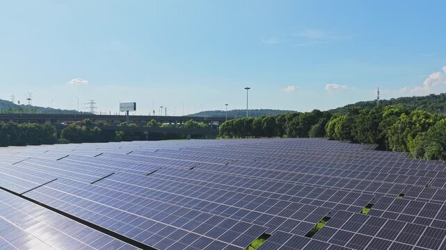 Drone rising above solar panels to reveal roads and city edge