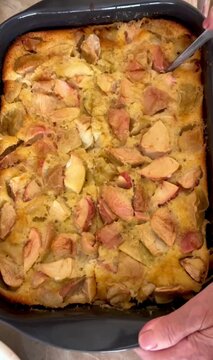 Hand Cutting Homemade Apple Cake in Baking Dish 