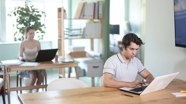 Man staff working at laptop computer in office room space. Day in office of business structure, manager working at computer. Hard work, multitasking, efficient execution of tasks
