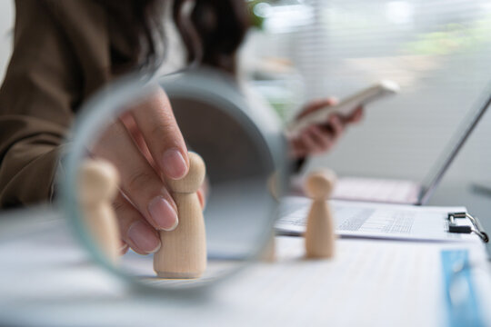 Female HR professional reviewing candidates with a magnifying glass, supporting recruitment, screening and hiring decisions.