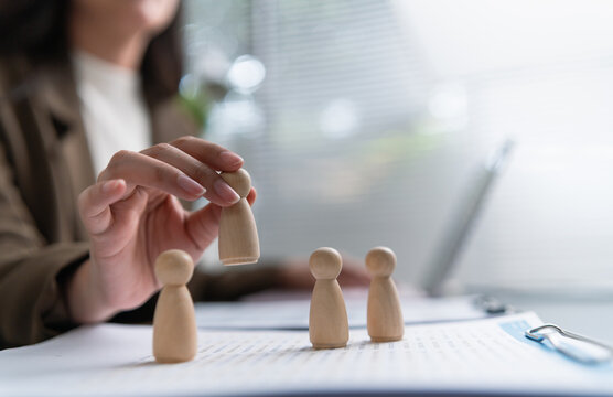 Asian Female HR manager selecting the best candidate for recruitment using wooden figures, symbolizing hiring, evaluation, and talent acquisition.